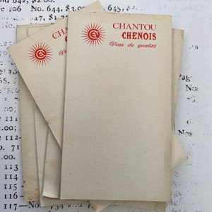 Könnte beinhalten: Ein Stapel alter Papierkarten mit dem roten Text "CHANTOU CHENOIS Vins de qualité". Die Karten zeigen ein Sonnenlogo und Alterserscheinungen. Im Hintergrund sind verblasste Texte und Zahlen zu sehen.