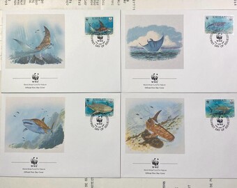 May include: Four stamps from Kiribati featuring different marine life. The stamps are blue and white with a red and white border. The stamps feature a manta ray, a shark, a whale shark, and a stingray. The stamps are part of a set of stamps celebrating the World Wide Fund for Nature.