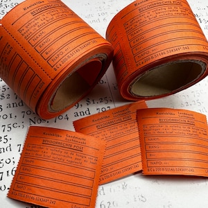 Può includere: Tre rotoli di etichette di carta arancione con testo nero. Le etichette sono per "Koninklijke Landmacht Bevoorrechte Post" e hanno campi per il nome, il rango e il numero NAPO. Il testo sulle etichette dice "De gebruiker is volledig op de hoogte van de bepalingen t.a.v. bevoorrechte post en heeft deze in deze brief volledig nageleeld."