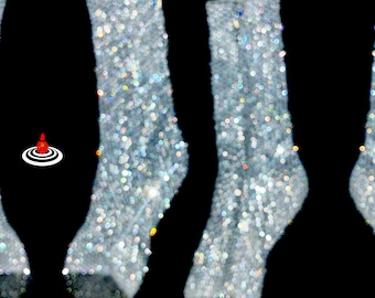 May include: A pair of crew-length socks covered in a dense layer of silver, light-reflecting glitter that creates a sparkling, multi-coloured effect against a solid black background. The socks feature a defined heel and toe area with a shimmering texture.
