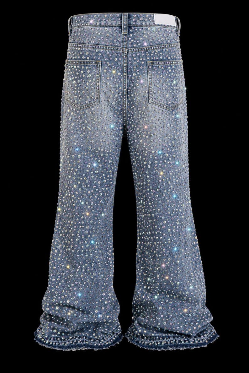May include: Light blue denim jeans heavily embellished with sparkling rhinestones. The jeans have a classic five-pocket design and a flared leg. The rhinestones are densely packed, creating a shimmering effect.