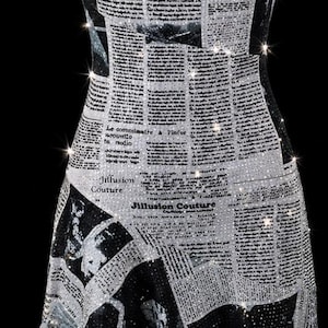 May include: A sleeveless dress featuring a black and white newspaper print pattern with sparkling rhinestone embellishments throughout. The garment has thin chain straps, a cowl neckline, and an asymmetrical hemline with the text Jillusion Couture.