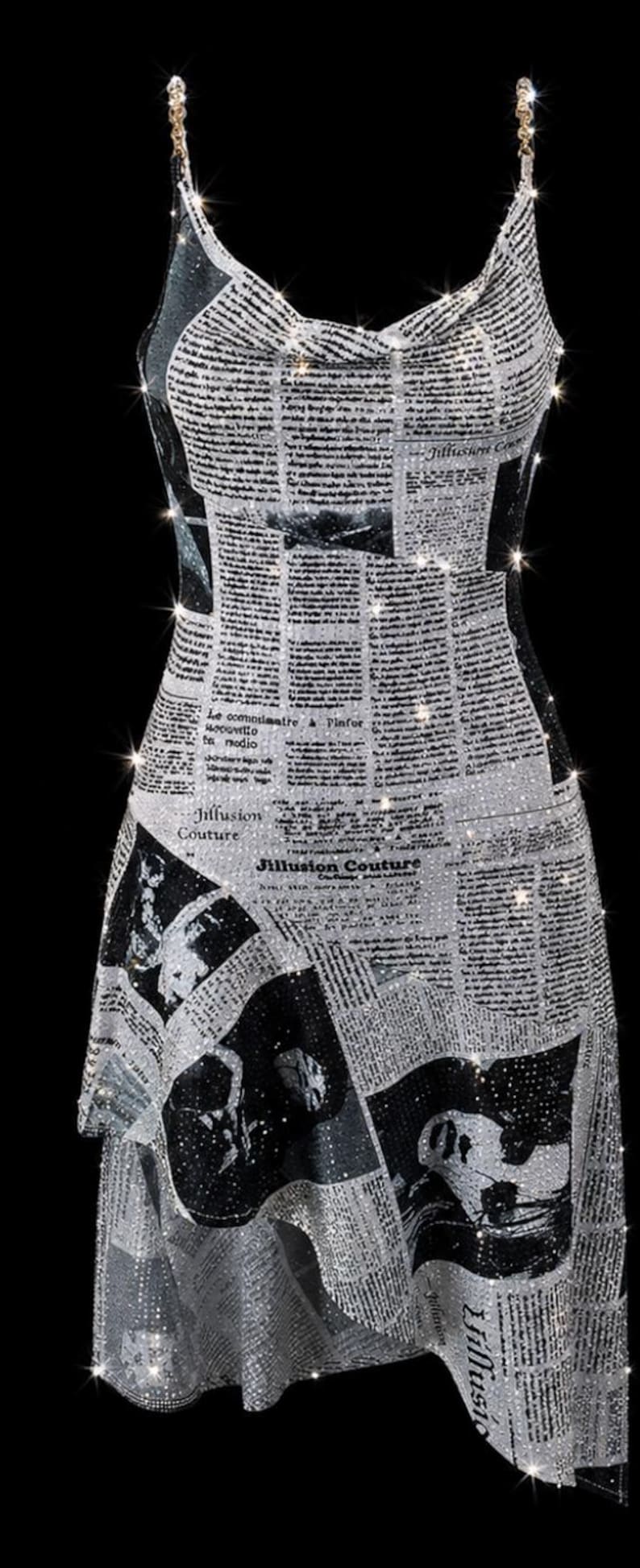 May include: A sleeveless dress featuring a black and white newspaper print pattern with sparkling rhinestone embellishments throughout. The garment has thin chain straps, a cowl neckline, and an asymmetrical hemline with the text Jillusion Couture.