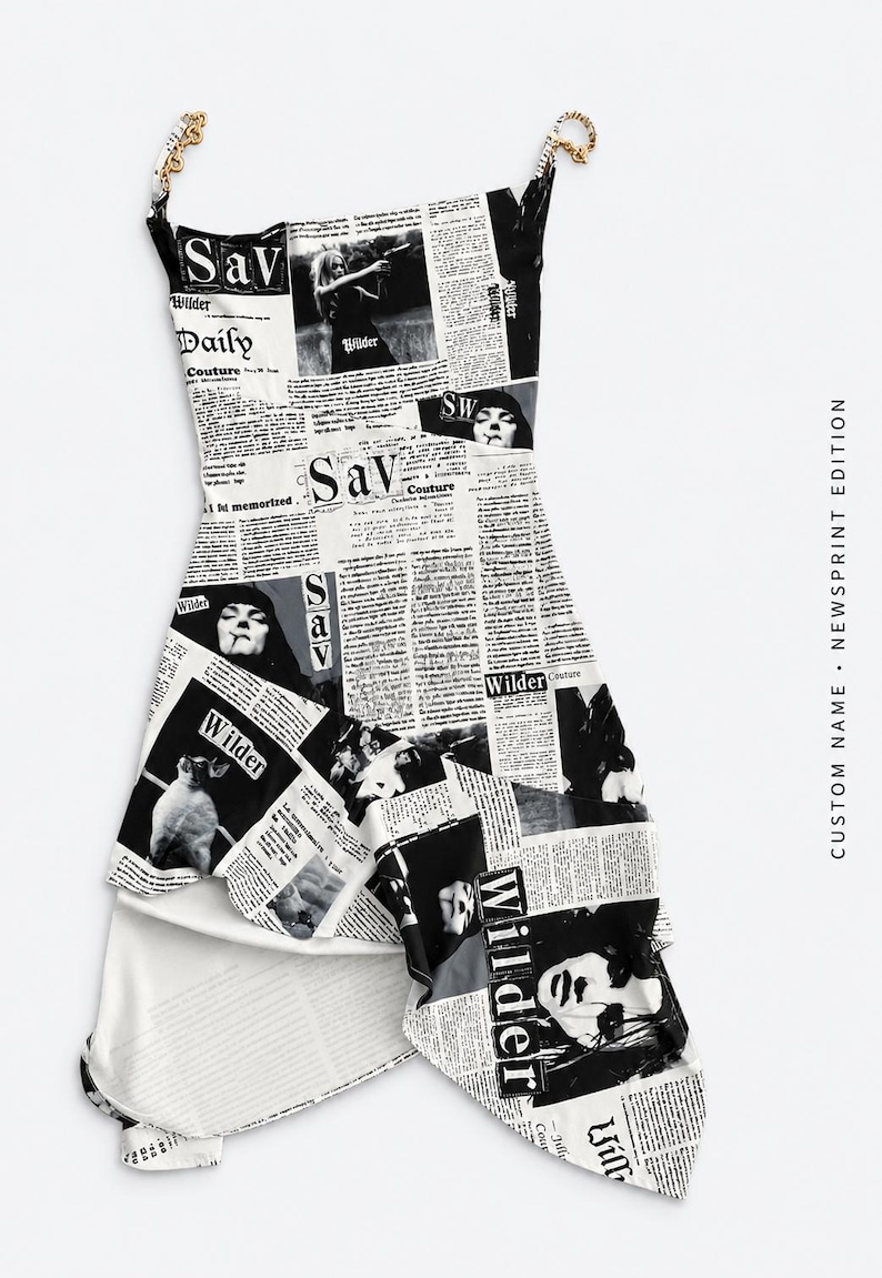 May include: A sleeveless dress featuring a black and white newspaper print pattern with photographic images and the text Sav Wilder Daily Couture. The garment has thin gold-toned chain straps and an asymmetrical hemline with a layered skirt design.