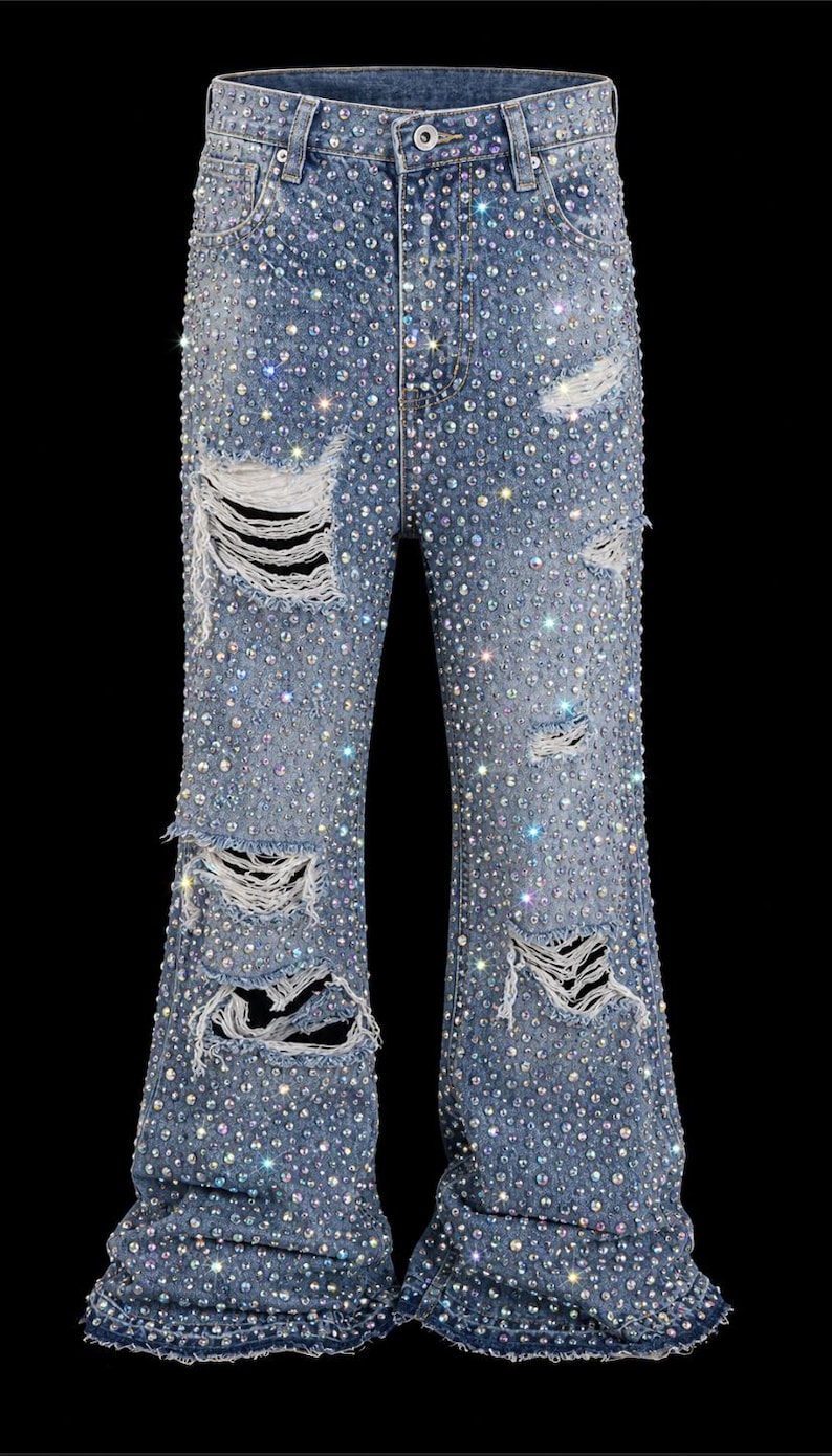 May include: Light blue denim jeans with distressed details and embellished with numerous sparkling rhinestones. The jeans have a flared leg design and are set against a black background.