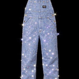 Könnte beinhalten: Hellblaue Jeans-Latzhose mit funkelnden Strasssteinen verziert. Die Latzhose hat klassische Latz-Taschen, verstellbare Träger und messingfarbene Knöpfe. Ein einzigartiges und auffälliges Mode-Statement.