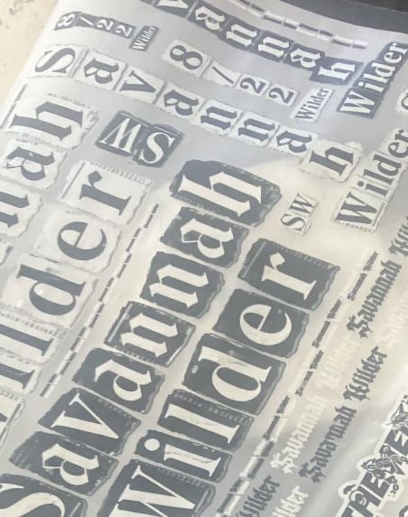 May include: A transparent sheet featuring multiple repeating black and white decals of the text Savannah Wilder and the numbers 8/22. The designs are presented in various sizes and orientations, showcasing a bold, serif typeface on rectangular backgrounds.