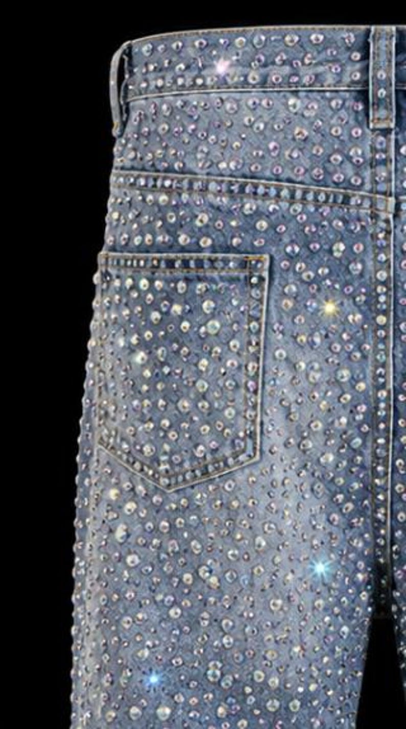 May include: Light blue denim jeans heavily embellished with sparkling rhinestones. The jeans feature a classic five-pocket design and a straight leg cut. The rhinestones are of varying sizes and create a dazzling effect. The jeans are a statement piece.