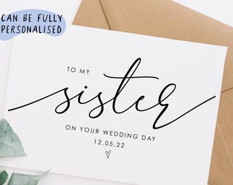 May include: A white card with black calligraphy that reads "To my sister on your wedding day 12.05.22" with a small heart symbol.