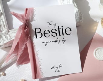 May include: A white card with a pink ribbon tied around it. The card says "To my Bestie on your wedding day" and "all my love Kelly".