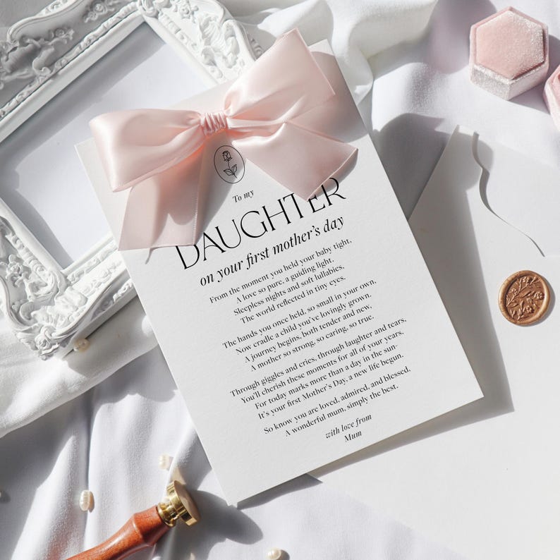 May include: A white card with a pink ribbon tied around it. The card has black text that reads "To my Daughter on your first mother's day". The text continues with a poem about motherhood.