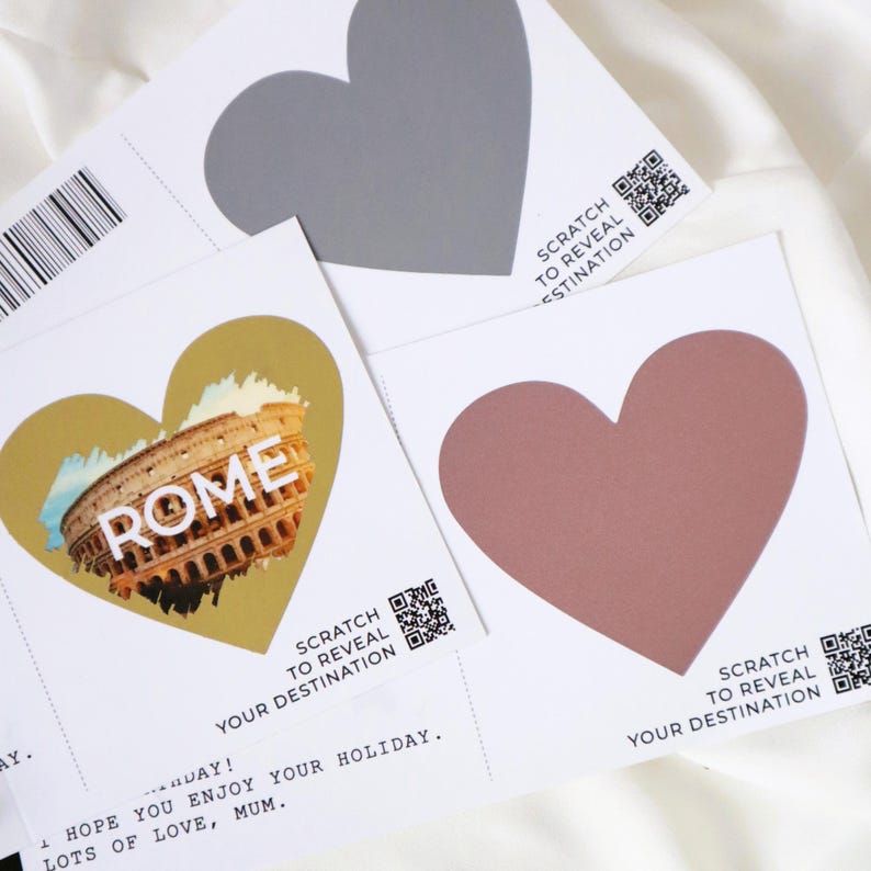 May include: Three scratch-off cards with heart-shaped areas to reveal a destination. The cards have the text "Scratch to reveal your destination" and a QR code. One card has a gold heart with the word "ROME" and a picture of the Colosseum.