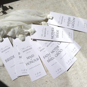 May include: White place cards with black text, reading "This seat is reserved for the Bride", "This seat is reserved for the Maid of Honour", "This seat is reserved for the Mother of the Bride", "This seat is reserved for the Father of the Groom", and "This seat is reserved for the Father of the Groom".