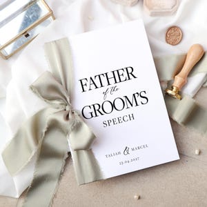 May include: A white booklet with the text "Father of the Groom's Speech" in black. The booklet is tied with a sage green ribbon and has the names "Taliah & Marcel" and the date "25.04.2027" printed on the bottom.
