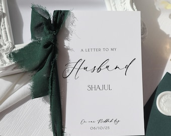 Peut inclure: Une carte blanche avec le texte "A Letter to My Husband Shajul On our Nikkah by 06/10/25" en écriture noire. La carte est décorée d'un ruban vert.