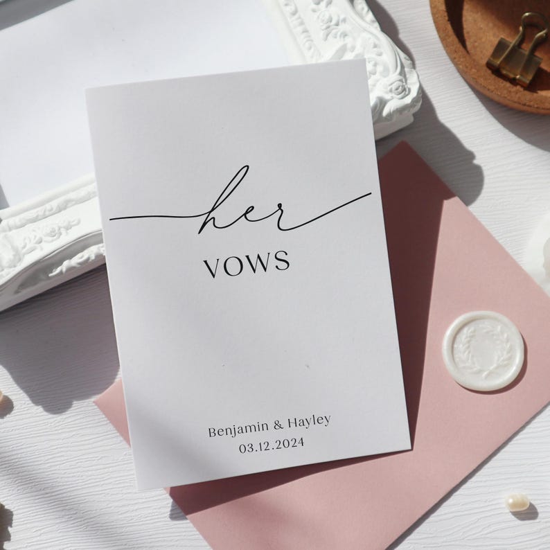 May include: A white card with the text "her vows" in black cursive script. Below the text is the date "03.12.2024" and the names "Benjamin & Hayley".