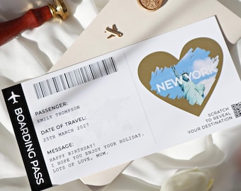 Könnte beinhalten: Eine weiße Bordkarte mit schwarzem Text, der "Boarding Pass", "Passenger: Emily Thompson", "Date of Travel: 25th March 2027" und "Message: Happy Birthday! I hope you enjoy your holiday. Lots of love, Mum." lautet. Auf der rechten Seite der Karte befindet sich ein goldener herzförmiger Aufkleber mit einem blauen und weißen Bild der Freiheitsstatue und dem Text "New York". Der Aufkleber hat einen Rubbelbereich mit dem Text "Scratch to reveal your destination".
