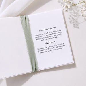 May include: An open white greeting card featuring a sage green frayed ribbon across the center. The text reads: Printed Inside Message Your message will be professionally printed on an additional inner page, creating a beautiful keepsake booklet with a luxurious finish. Blank Option No additional inner page is included. The inside of the card is left blank for your own handwritten message.