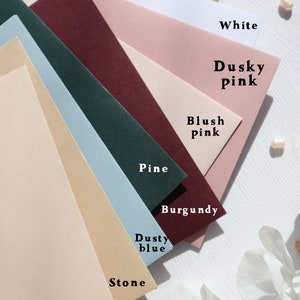 May include: A collection of ten different colored envelopes, arranged in a fan shape. The colors are: Tan, White, Dusky Pink, Blush Pink, Pine, Burgundy, Dusty Blue, Stone, and Biscuit.