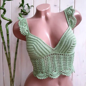 May include: A green crocheted crop top with a V-neck and a scalloped hem.