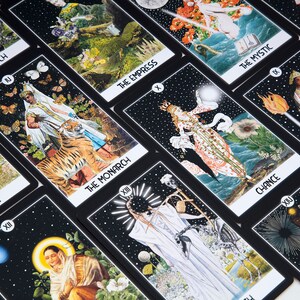 Pu&ograve; includere: Un set di carte dei tarocchi con sfondi neri e illustrazioni colorate. Le carte presentano vari personaggi e simboli, tra cui una strega, l'imperatrice, il monarca e la fortuna. Le carte sono disposte in una griglia.