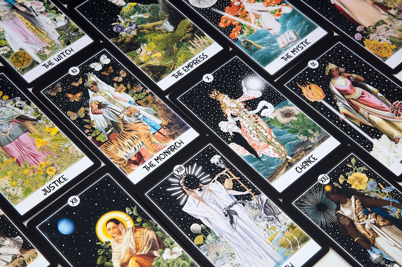 Pu&ograve; includere: Un set di carte dei tarocchi con sfondi neri e illustrazioni colorate. Le carte presentano vari personaggi e simboli, tra cui una strega, l'imperatrice, il monarca e la fortuna. Le carte sono disposte in una griglia.