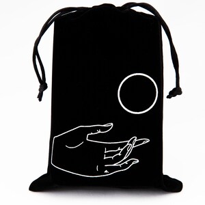 May include: Black velvet drawstring bag with a white embroidered design of a hand holding a circle.