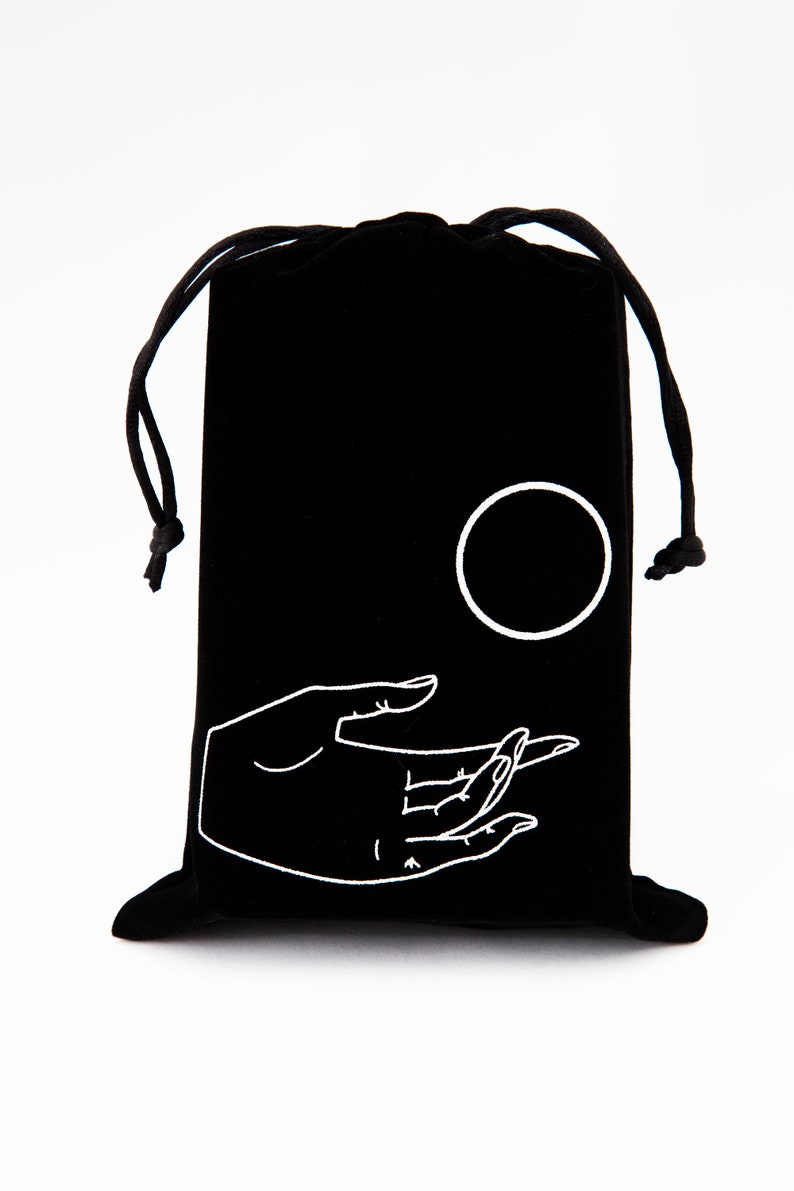May include: Black velvet drawstring bag with a white embroidered design of a hand holding a circle.