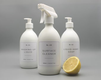Op de afbeelding: Drie witte plastic flessen met pompjes en etiketten. De flessen zijn gelabeld met "No. 41 Washing-Up Liquid", "No. 40 Surface Cleaner" en "No. 42 Liquid Hand Soap". De flessen staan op een grijs oppervlak met een citroenwig voor de fles handzeep.