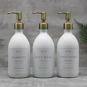 May include: Three white bottles with gold pumps and labels. The bottles are labeled "No. 27 Shampoo 100% Organic", "No. 28 Body Wash 100% Organic", and "No. 29 Conditioner 100% Organic". Each bottle is 500 ml or 16.91 fl oz.