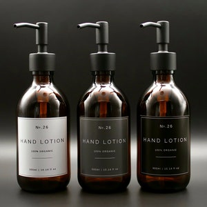 May include: Three amber glass bottles with black pump tops and labels that read "No. 26 HAND LOTION 100% ORGANIC 300ml | 10.14 fl oz".