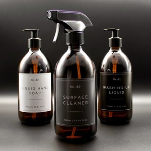 May include: Three amber glass bottles with black pump tops and labels. The labels are white with black text. The bottles are labeled "No. 42 Liquid Hand Soap", "No. 40 Surface Cleaner", and "No. 41 Washing-Up Liquid".