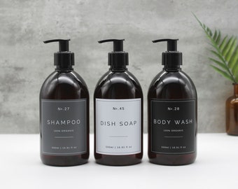 May include: Three amber glass bottles with black pump tops and white labels. The labels have black text that reads "No. 27 Shampoo 100% Organic", "No. 45 Dish Soap", and "No. 28 Body Wash 100% Organic". Each bottle contains 500 ml or 16.91 fl oz.