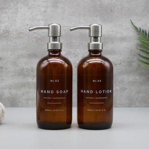 May include: Two amber glass bottles with stainless steel pumps, labeled "No. 03 HAND SOAP NATURAL INGREDIENTS 500ml | 16.9 fl oz" and "No. 04 HAND LOTION NATURAL INGREDIENTS 500ml | 16.9 fl oz".