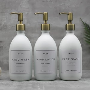May include: Three white, matte-finish pump bottles with gold-colored pumps. Each bottle has a label with black text: "HAND WASH", "HAND LOTION", and "FACE WASH". The bottles are labeled "100% ORGANIC" and hold 500ml / 16.91 fl oz.