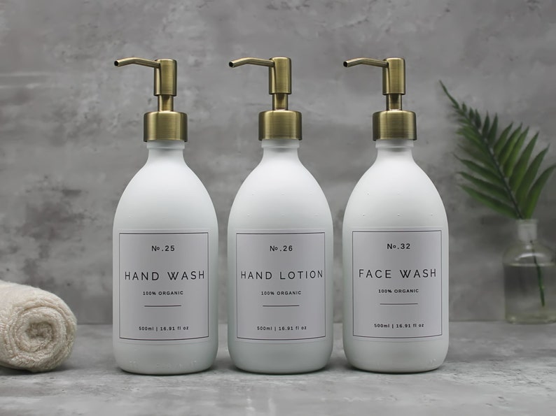 May include: Three white, matte-finish pump bottles with gold-colored pumps. Each bottle has a label with black text: "HAND WASH", "HAND LOTION", and "FACE WASH". The bottles are labeled "100% ORGANIC" and hold 500ml / 16.91 fl oz.
