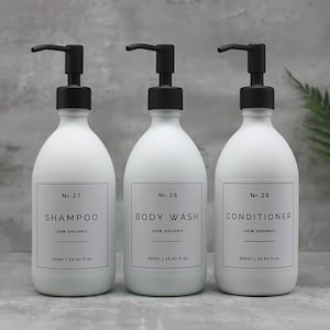 Pode incluir: Três garrafas brancas com tampas de bomba pretas e etiquetas. As garrafas são etiquetadas como "No. 27 Shampoo 100% Orgânico", "No. 28 Gel de Banho 100% Orgânico" e "No. 29 Condicionador 100% Orgânico". Cada garrafa contém 500 ml ou 16,91 fl oz.