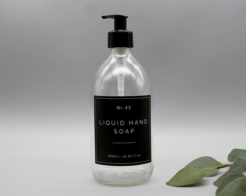 Puede incluir: Una botella de vidrio transparente con un dispensador de bomba negro lleno de jab&oacute;n l&iacute;quido para manos. La botella tiene una etiqueta negra con texto blanco que dice "No. 42 LIQUID HAND SOAP 500ml | 16.91 fl oz".