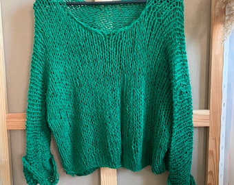 May include: Green knitted sweater with a loose fit and a wide neckline. The sweater has a crocheted texture and is made of a lightweight material.