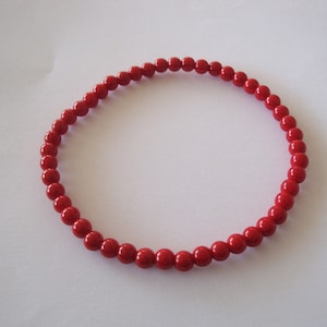 May include: A red beaded bracelet made of small, round beads.