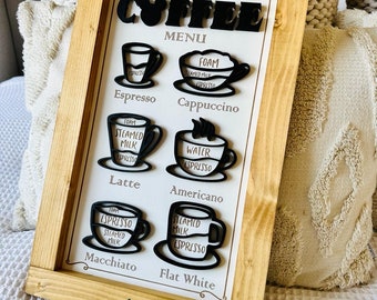 May include: A wooden sign with a white background and black lettering that says "Main Street Coffee Menu". The sign has a variety of coffee drinks listed with illustrations of coffee cups and the ingredients for each drink.