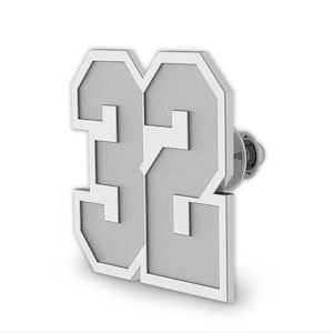 May include: Silver-toned metal pin in the shape of the number 22. The number is outlined in a slightly raised border.