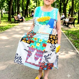 May include: A sleeveless patchwork dress featuring a vibrant mix of fabrics, including a large sunflower print, floral patterns, polka dots, and a graphic panel depicting two figures in white silhouettes against a red plaid background.