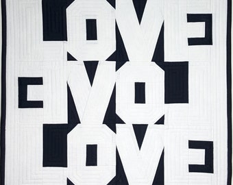 Puede incluir: Una colcha negra y blanca con la palabra "LOVE" repetida tres veces en un patrón geométrico.