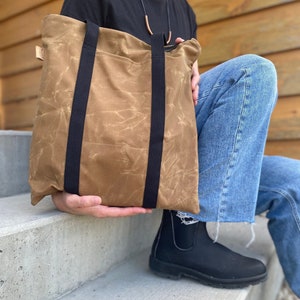 Sac fourre-tout en toile cirée pour homme et femme. Sac à bandoulière fin en toile cirée avec fermeture éclair et poches pour ordinateur portable et articles essentiels.