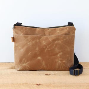 Sac à bandoulière en toile cirée pour femme et homme, avec fermeture éclair sur le dessus et poche extérieure.Sac en toile cirée robuste pour l'extérieur et les voyages.