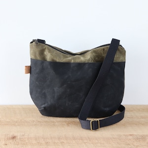Sac à bandoulière arrondi multicolore en toile cirée, avec fermeture éclair sur le dessus et poche extérieure. Sac en toile cirée robuste pour l'extérieur et les voyages.