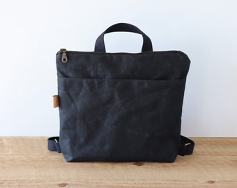 May include: A black canvas backpack with a top handle and adjustable straps. The bag has a zipper closure and a front pocket.