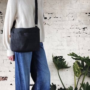 Sac à bandoulière en toile cirée pour femme et homme, avec fermeture éclair sur le dessus et poche extérieure.Sac en toile cirée robuste pour l'extérieur et les voyages.
