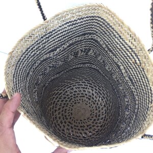 May include: A black and natural woven tote bag with two handles. The bag is made of a natural material and has a black and white pattern.